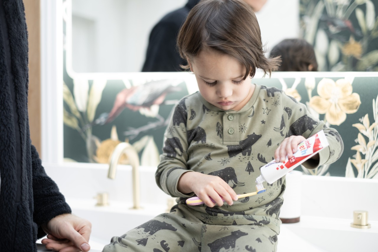 Child squeezing Aquafresh toothpaste on toothbrush